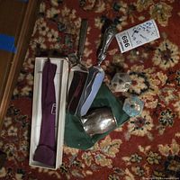 Group view of all items on rug—servers, creamer, finials, box, pouch, weight tag