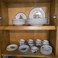 Full cabinet view showing stacks of dinner plates, salad plates, cups, saucers and bowls