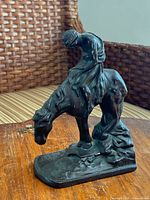 Front three-quarter view of bronze figurine showing rider on horse and signature on base