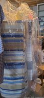 Striped blue and beige comforter and striped grey and white comforter sealed in plastic