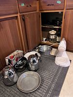 Overview of lot under cabinet showing waffle maker, blender base, kettles, pans