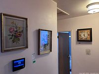 Three of the framed needlepoint pieces hanging on wall, including clock piece