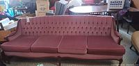 Front view of full pink velvet sofa with three seat cushions and tufted back
