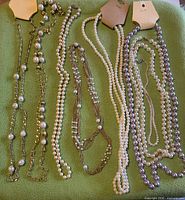 overview of all eight necklaces laid out on green background