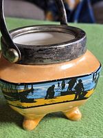 Jar front showing orange lustre glaze, maritime silhouette panel, EPNS rim and handle