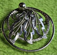 front view of sterling silver circular brooch with openwork feather motif