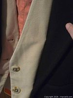 Close-up of white-beige vest panel with buttons beside black outer layer