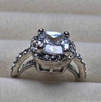 Front view of silver-tone ring showing cushion-cut solitaire and halo