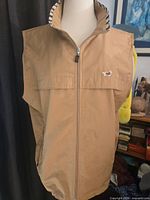 Front view of tan DAKS sleeveless vest on mannequin