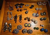 Full drawer view of 23 pairs of clip-on earrings laid out