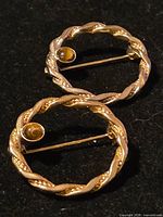 Front view of both brooches on dark background