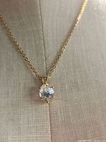 Close-up of faux diamond solitaire pendant on gold tone chain