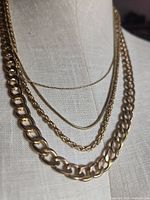 Front view of layered gold-tone necklace on dress form