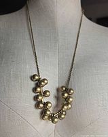 Front view of entire necklace on mannequin showing clustered brass balls
