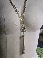 Full view of necklace on dress form showing length, link styles, and tassel
