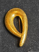 Front view of gold-tone hammered teardrop brooch