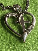 Close-up of pendant showing heart outline, cross, rhinestones, bail and part of chain