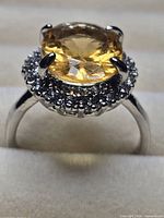 Ring front view showing yellow center stone and halo of clear stones