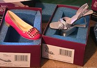 Both miniature shoes in their boxes showing labels and foam inserts