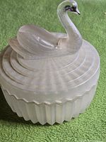 Frosted glass trinket box with lid on, showing swan and lipstick slot