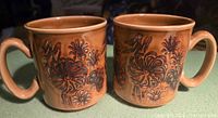 Pair of Winchcombe brown stoneware mugs front view showing raised floral and bird motif