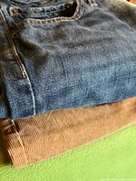 Folded blue jeans and brown corduroy pants showing fabric and colors