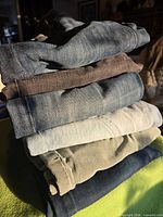 Stack of six folded denim jeans showing assorted washes
