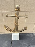 Front view of gold-tone anchor sculpture on white marble base