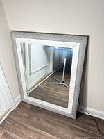 Full view of framed mirror leaning against wall