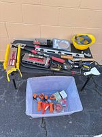 Overall view of table with assorted hand tools and clear tote below
