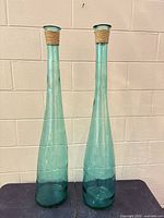 Full view of both matching aqua glass vases standing side by side