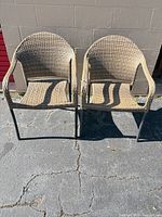 Front view of both woven wicker patio armchairs showing overall design and condition