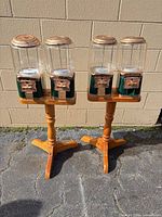 Two wooden pedestal stands each holding two coin-operated vending heads