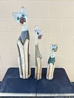 Front view of all three carved wooden cats standing on table