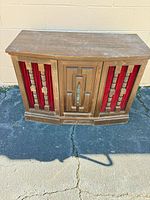 Front view of wood console stereo cabinet with red cloth speaker grilles