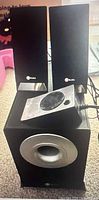 Subwoofer, two satellite speakers, wired controller atop subwoofer
