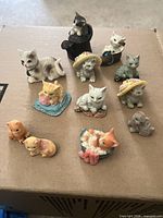 Group shot of all 12 cat figurines on cardboard surface