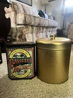 Front view of Bassett's octagonal tin beside gold cylindrical tin
