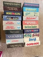 Stack of VHS spines showing titles such as Home Alone, Shrek 2, Splash, Rain Man, Benji