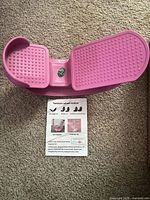 Pink tension wheel trainer shown from top with instruction sheet