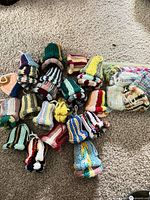 Group of knit bell ornaments spread on carpet with additional pieces in zipper bag
