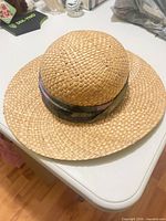 Top and side view of woven straw sun hat showing brim and fabric band
