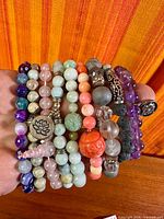 Group of stacked gemstone bead bracelets held in hand