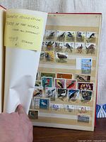 Album cover opened to page showing mounted bird stamps and note indicating thematic collection