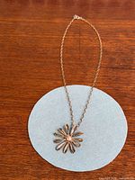 Full view of necklace with flower pendant on chain