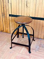Full view of stool showing wood seat and arched iron legs