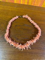 Full view of coral necklace laid flat showing graduated design