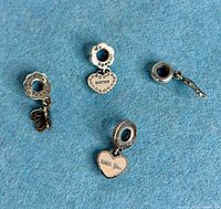 All four Pandora sterling silver charms displayed on blue felt