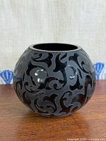 Full view of spherical charcoal glass vase with black scroll overlay