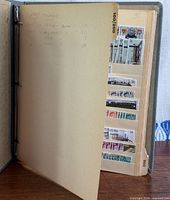 Album open showing index page and first stock page with train, military, space, music stamps